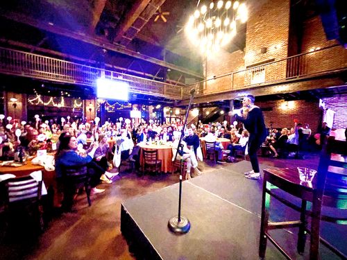 Debbie Scheer benefit auctioneer on stage at nonprofit gala Denver Colorado