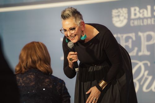 Debbie Scheer benefit auctioneer on stage at nonprofit gala Denver Colorado