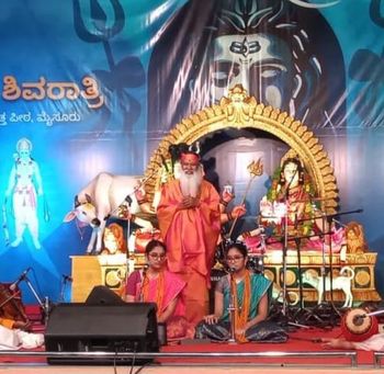 Pujya Appaji stands in the form of Lord Dattathreya (kindly zoom in) behind Sarvepalli Sisters during one of their concerts
