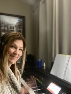 Pamela Dio beside a grand piano and sheet music in a theatre