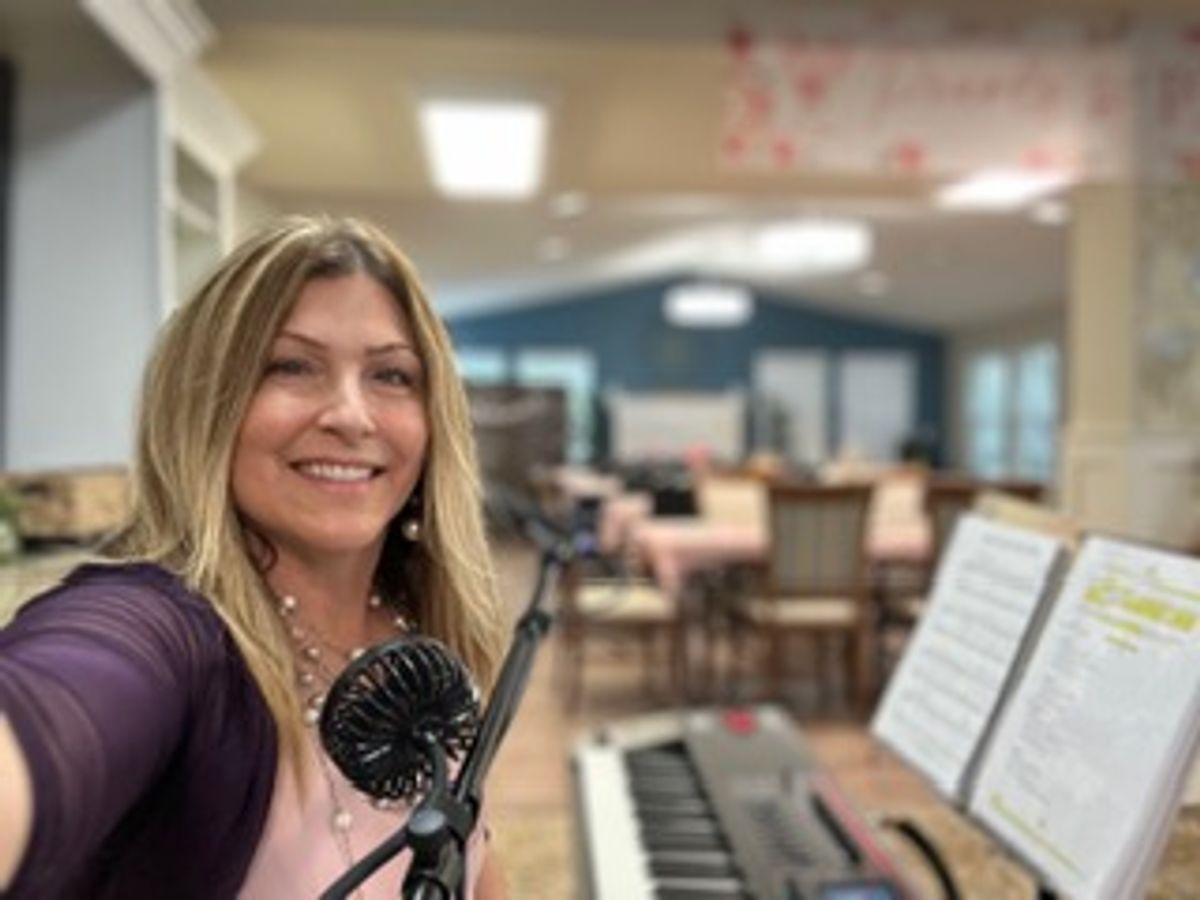 Pamela Dio at the keyboard and microphone in a senior-community setting