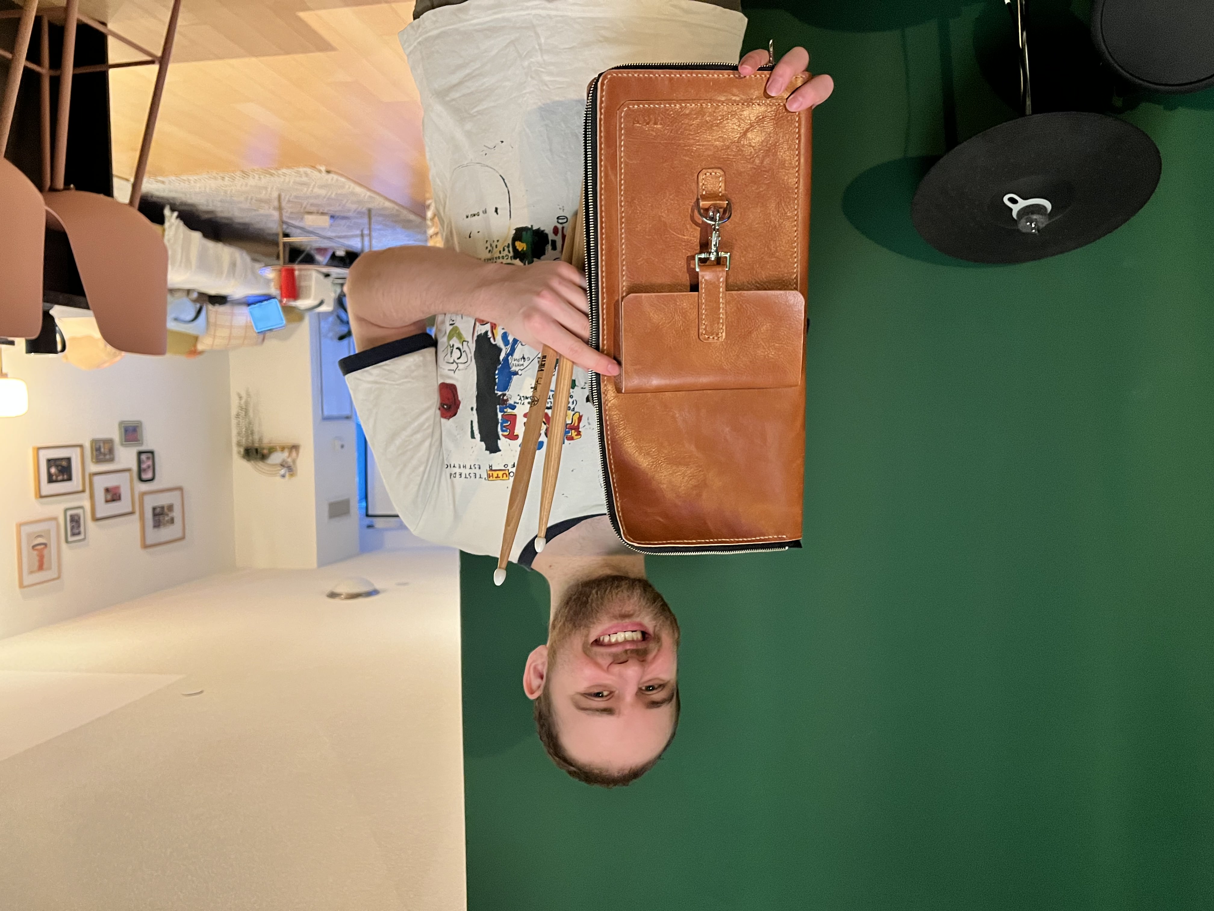 Michael Friedman holding a handmade leather drumstick bag made by Tracy Pham
