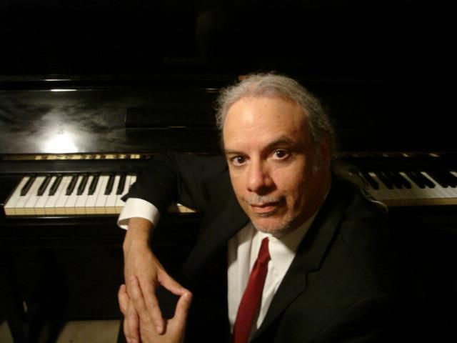Arthur Cruz wearing a suit and tie at the grand piano