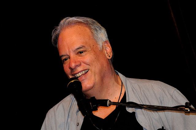 Arthur Cruz similes at the mic as he performs singing and playing piano for his happy audience in Miami, Florida