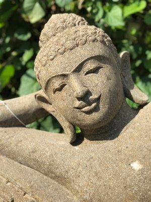A reclining stone buddha in a garden.